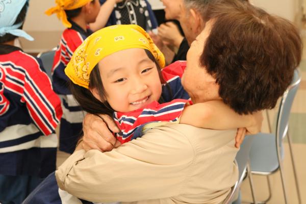 サプライズでおばあさんに抱きつく笑顔の園児の写真