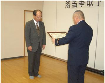 写真：表彰を受ける苫米地司・北海道工業大学学長