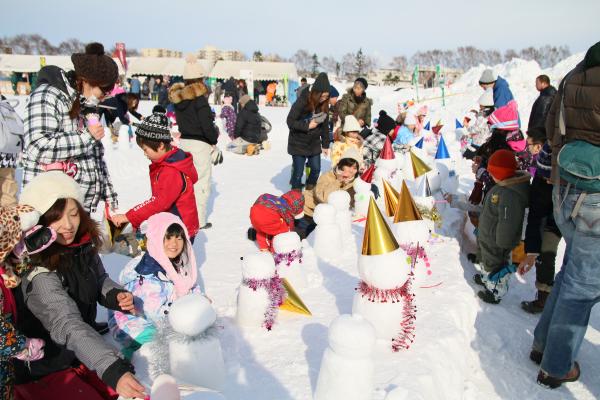 雪だるまの装飾コーナーで楽しむ親子の写真