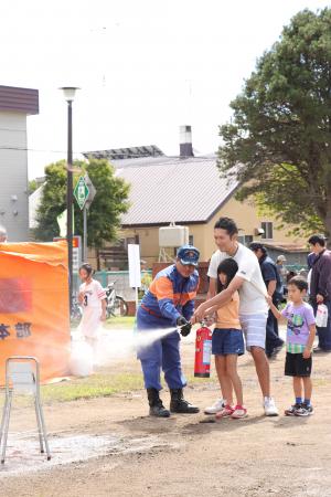 消防職員と一緒に消火体験をする親子の写真