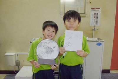 サインを手に笑顔の子どもの写真