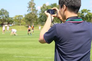 ラグビーの交流試合の写真を撮る竹田さん