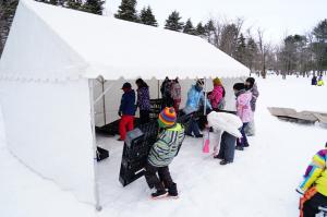 ひんやり王国で雪中キャンプのための寝床を作る参加者の写真