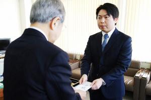 防犯ブザーの目録を手渡す株式会社スコレーの片岡和希取締役の写真
