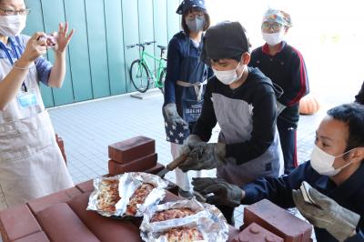 焼きあがったピザを窯から出す男の子の写真