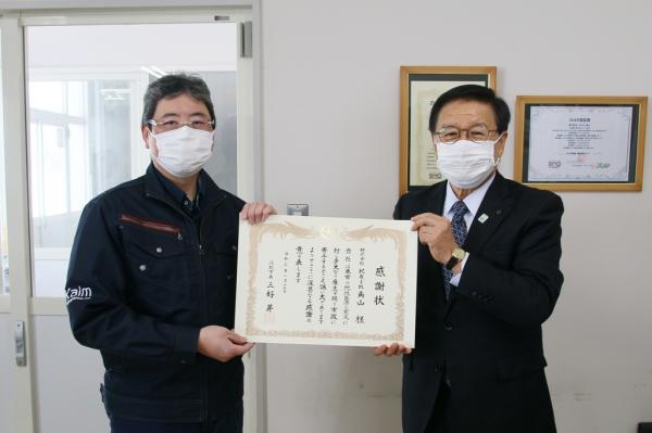 Ｋａｌｍ角山から乳製品の寄贈を受ける江別市長の写真