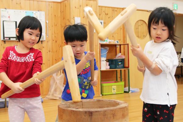真剣な顔で餅をつく3人の園児