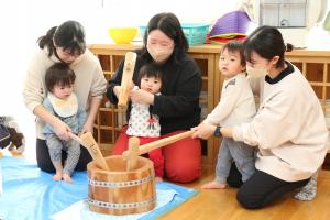 保育士と一緒に餅をつく3人の園児