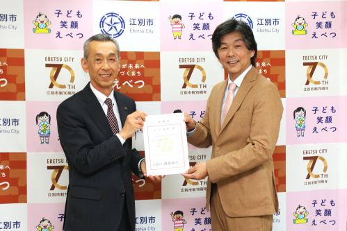 市長からヒロ福地氏へ辞令を渡す様子